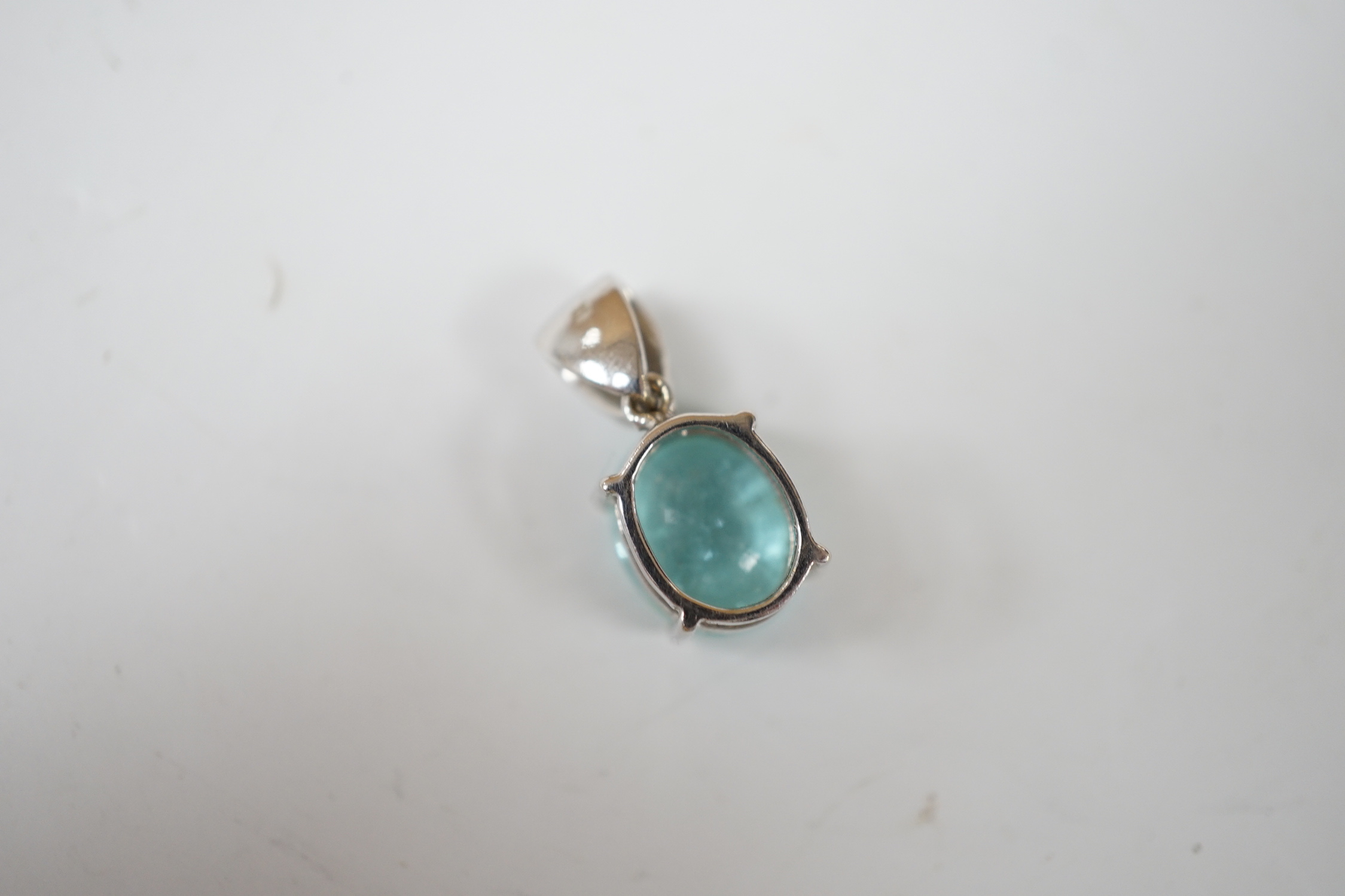 An 18ct white gold and single stone oval cut paraiba tourmaline pendant, with single stone diamond set bale, overall 19mm, gross weight 3.7 grams.